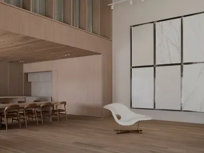 Modern living room with wooden floors, a white wall with a painting, a dining table, a couch, and natural light from windows