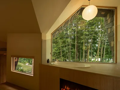 Well-lit bathroom with a wooden design, a large window, a bathtub, and a fireplace, creating a cozy and inviting atmosphere