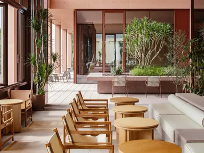 A modern restaurant space with comfortable seating, various chairs, and dining tables, decorated with potted plants and natural light