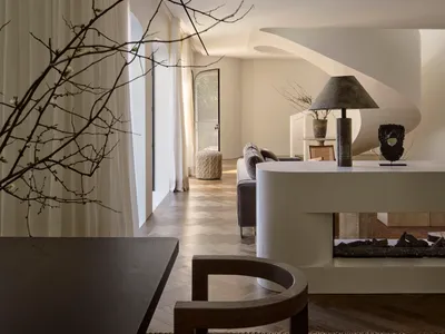 Cozy living room with a fireplace, wood furniture, and white walls, lit by natural sunlight
