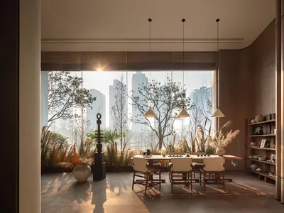 A well-lit dining room with a wooden dining table and chairs, surrounded by a modern open-concept space with a large window and natural light