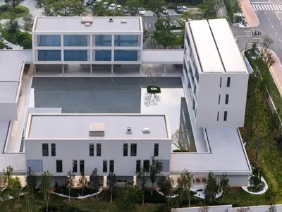 A large white building with a pool in the center, surrounded by a deck, in a modern architectural style with a sense of luxury and sophistication