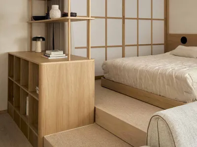 Cozy bedroom with a bed, bookshelf, and wooden floor, well-lit and inviting