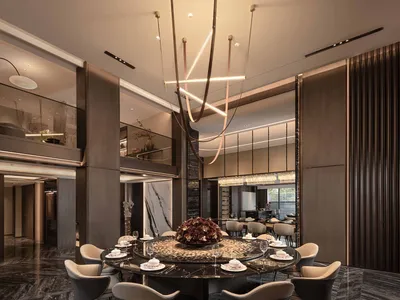 A modern dining room with a round table, chairs, wine glasses, and vases, lit by a chandelier and natural light