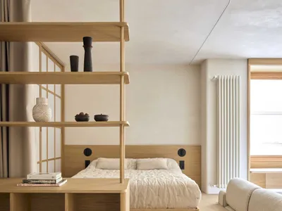 Cozy bedroom with a bed, bookshelf, and couch, featuring wood furniture and a neutral color palette