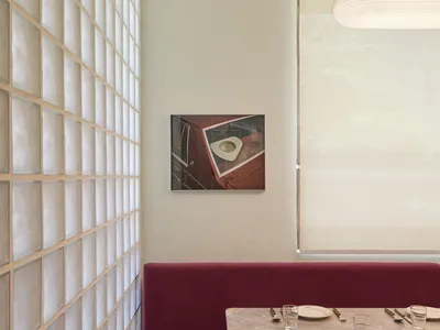 一間充滿光照的餐廳，紫色沙發、餐桌和餐具、掛在桌上的畫作