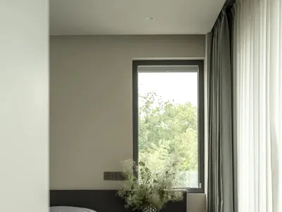 Cozy bedroom with a bed against the wall and a window above it, featuring a black and white color scheme and natural light