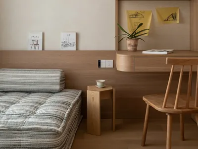 Comfortable living space with wooden floors and walls, a couch, dining table, chair, and potted plant, well-lit for a warm atmosphere