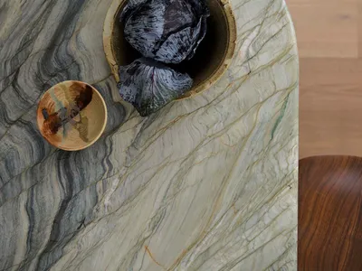 A photograph of a marble countertop with a bowl placed on it, set in a kitchen or dining area with natural or ambient lighting