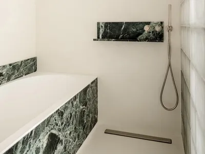 現代浴室內，白色浴缸、淋浴設備和光纖組合磚 countertops，安置在一間清潔線條和簡約設計元素的 dimly lit 空間中