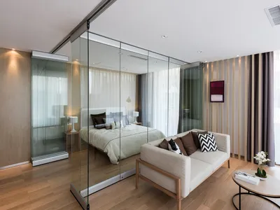 A well-lit living room with a couch, bed, and chair, arranged to maximize space, and a large glass door that brings in natural light