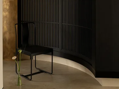 A dimly lit living room with a black chair and a potted plant, featuring a black and white color scheme