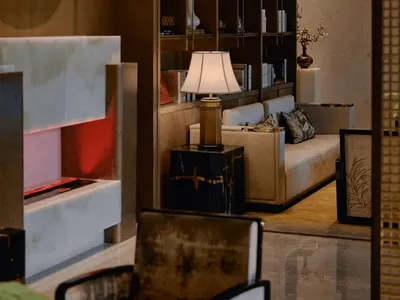 Cozy modern living room with a couch, chair, lamp, bookshelf, and fireplace, decorated with books and warm dim lighting