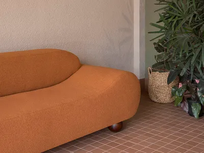 A well-lit living room with a brown couch and a potted plant, creating a comfortable and inviting atmosphere