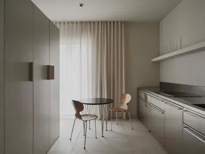 一間充滿光線的現代廚房和餐廳區域，用著木製桌子和椅子，水槽、冰箱和窗戶