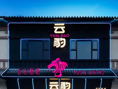 一座黑色的建築物，擁有外用外語的霓虹燈招牌，創造出活躍且吸引人的氛圍