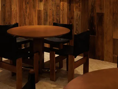 餐廳擁有木質牆壁和木質餐桌，周圍是黑色椅子，在昏暗的空間中