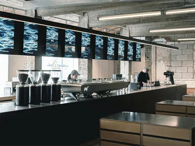 Sleek modern kitchen with wooden countertops, appliances, and a large island, lit by bright overhead lighting
