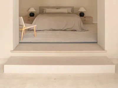 A cozy bedroom with a bed, chair, and lamp, featuring wood and fabric materials, soft lighting, and a focus on relaxation