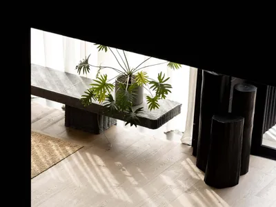 Cozy living room with a hardwood floor, a bench, a potted plant, and a vase, well-lit and inviting