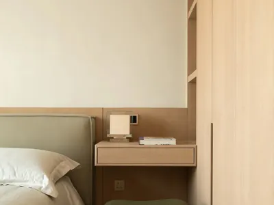 Cozy bedroom with a bed, chair, and desk, featuring wooden furniture and a white color scheme, with soft and warm lighting