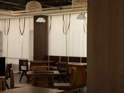 Cozy restaurant dining area with wooden tables and chairs, dim lighting, and a warm atmosphere