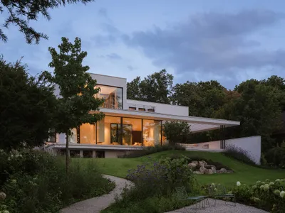 A modern house with a large open living room, dining area, and kitchen, featuring a fireplace, sliding glass door, and natural light