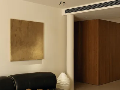 Cozy living room with a black couch, chair, and dining table, featuring a white wall, brown wooden door, and decorative elements