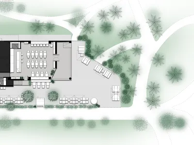 A modern restaurant with a black roof and white exterior in a well-lit courtyard setting, surrounded by a road and possibly a dining area