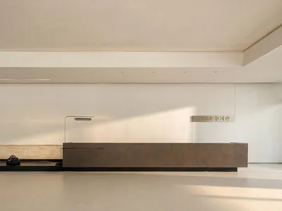 A cozy living space with a brown wooden bench and table, surrounded by a white wall and natural light from a window