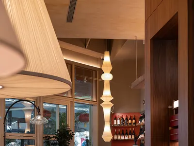 Cozy restaurant dining area with multiple tables, chairs, potted plants, and dim lighting, featuring a combination of wood and metal elements