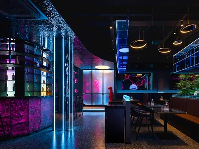 A modern restaurant interior with a bar, large window, and comfortable seating area with wooden furniture and potted plants, creating a warm and inviting atmosphere