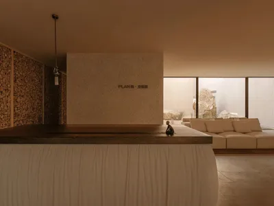 A modern living room with a large couch and small table, featuring a large window for natural light and predominantly white materials for a clean and bright appearance