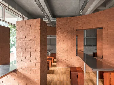 A modern dining space with a brick wall, wooden floor, and natural light from a window, featuring a dining table and chairs