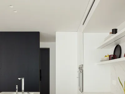 Modern kitchen with wooden floors, white cabinets, and natural light from windows