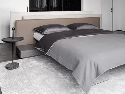 Cozy bedroom with a bed, nightstand, and dresser in a grey color scheme, with dim lighting and wood and fabric materials