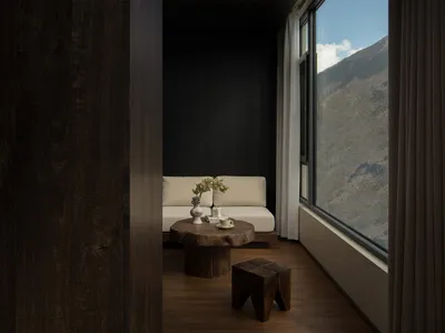 Cozy living room with a wooden floor, a couch, coffee table, and a window with a view of a mountain, well-lit by natural light
