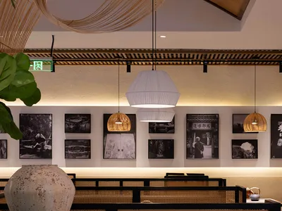 A modern restaurant interior with tables, chairs, artworks, and hanging lights creating a warm and inviting atmosphere