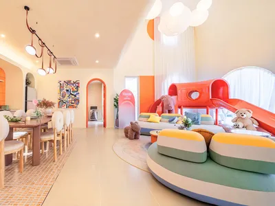 Vibrant living room with colorful furniture, a couch, chair, potted plant, dining table, and natural light from windows