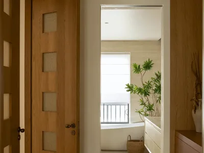 Bathroom with a wooden door, white bathtub, sink, and natural light from a window