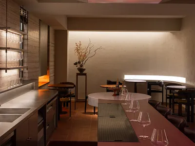 一個現代餐廳的長桌子、木製椅子和酒杯,在燈具下面,創造出高雅的氛圍