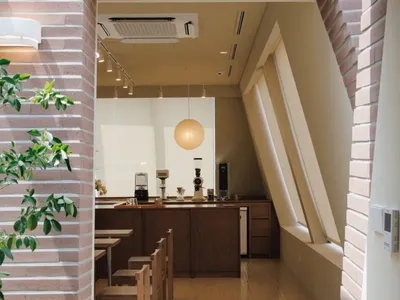 Dining area with wooden tables, chairs, and tableware, lit by natural light and warm ambiance