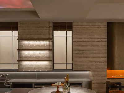 A dimly lit bar with a marble countertop, a wine bottle, and a wine glass, set in a modern restaurant or bar space