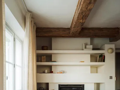 Cozy living room with a fireplace, chair, and bookshelf, featuring wood and stone materials and dim lighting