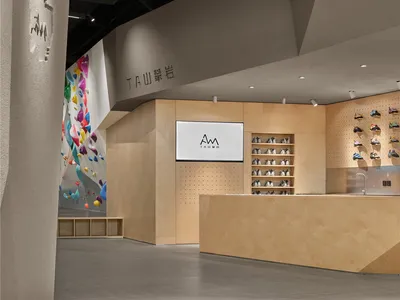 A dimly lit shoe store with a wooden counter and TV on the wall, surrounded by displayed shoes
