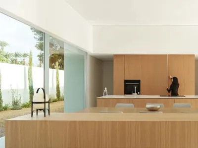 Modern kitchen with wooden cabinets, a white countertop, and natural light from a window