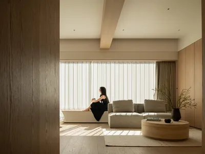 一間充滿自然光的家庭廳，裡面有沙發、一個大窗戶以及一名女性坐在上面享受著景色