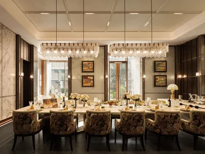 A dining room with a long wooden table and chairs, surrounded by wine glasses, cups, and vases, with a large window allowing natural light to enter, creating a warm and inviting atmosphere