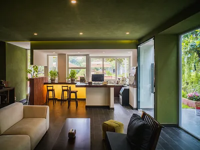 Cozy living room with a green color scheme, featuring a couch, dining table, and kitchen area, with a mix of green and brown colors and a warm atmosphere