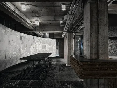 半暗的餐廳和廚房空間，具有一個混凝土地板、餐桌和餐桌台